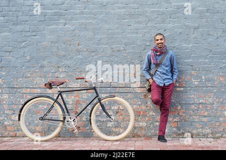 Warum fahren, wenn Sie fahren können. Porträt eines jungen Mannes, der mit seinem Fahrrad gegen eine graue Mauer in der Stadt posiert. Stockfoto