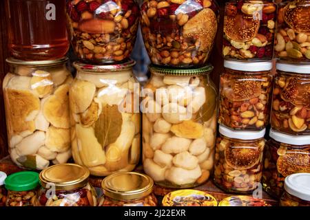Glas mit vielen Pilzen und Nüssen mit Honig in Glasgefäßen konserviert Stockfoto