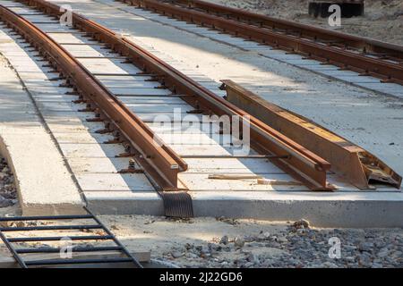 Reparatur von zwei-Wege-Straßenbahngleisen, Verlegung von Eisenschienen auf Stahlbetonballen, Aussicht auf eine Reparaturstelle bis zum Horizont. Stockfoto