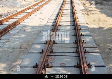 Reparatur von zwei-Wege-Straßenbahngleisen, Verlegung von Eisenschienen auf Stahlbetonballen, Aussicht auf eine Reparaturstelle bis zum Horizont. Stockfoto