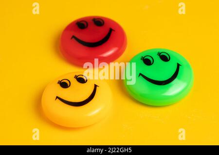 Grüner gelber und roter runder Magnet mit einem Lächeln in einer Reihe auf gelbem Hintergrund. Stockfoto