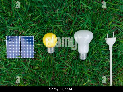 Photovoltaik-Solarpanel, Lampe, Steckdraht und mobile auf grünem Gras Hintergrund. Alternative saubere und erneuerbare Energien. Stockfoto