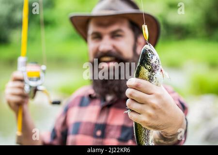 Angeln. Angler mit Angeltrophäe. Fischer und Forelle. Angelhintergründe. Mann hält große Fischforelle in den Händen. Fischer und Trophäe Forelle. Mann Stockfoto