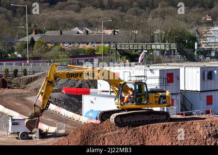 Taffs Well, Wales - März 2022: Person, die als großer mechanischer Bagger auf einem großen Haufen Schotter arbeitet. Stockfoto