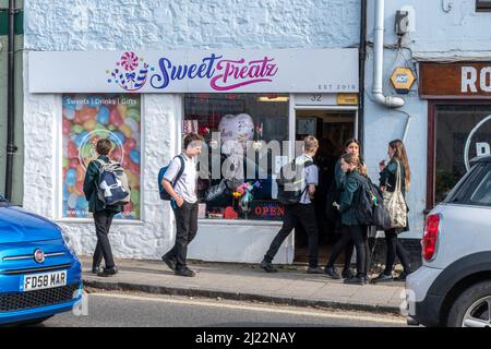 Schulkinder vor einem Süßgeschäft auf dem Weg von der Schule nach Hause, kaufen ungesunde Lebensmittel, Liphook, Hampshire, Großbritannien Stockfoto