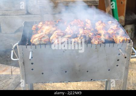 Nahaufnahme der Spieße beim Kochen auf dem Grill mit Rauch. Stockfoto