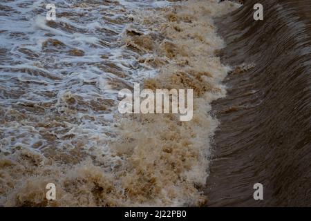 Wasser, das während einer Überschwemmung durch ein Wehr fließt Stockfoto