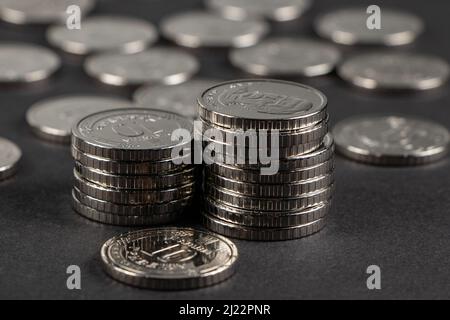 Ukrainische 10-Stunden-Münzen. Geld und Finanzen. Stapel von 10 Griwna-Münzen, auf dunklem Hintergrund. Ukrainische Münzen. Stockfoto