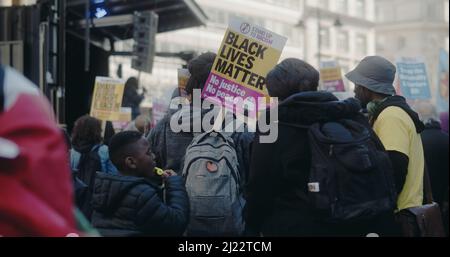 London, Großbritannien - 03 19 2022: Eine schwarze Frau mit einem Schild, ‘Black Lives Matter’, am Portland Place, zum jährlichen ‘Marsch gegen Rassismus’. Stockfoto