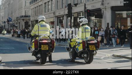 London, Großbritannien - 03 19 2022: Zwei städtische Polizeibeamte auf Motorrädern blockieren die Regent Street, zum jährlichen ‘Marsch gegen Rassismus’. Stockfoto