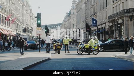 London, Großbritannien - 03 19 2022: Treffen von Polizeibeamten auf Motorrädern, die den Verkehr auf der Regent Street an der Abzweigung der Conduit Street steuern, für ‘Marsch gegen Rassismus’. Stockfoto