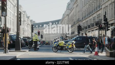 London, Großbritannien - 03 19 2022: Traf Polizeibeamter mit Motorrad, das den Verkehr auf der Regent Street an der New Burlington Turning kontrolliert, für einen Protest. Stockfoto