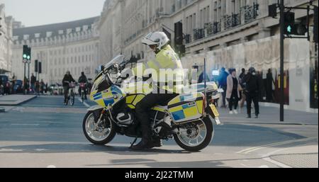 London, Großbritannien - 03 19 2022: Met Police Officer Aussteigen von Motorrad, um den Verkehr auf Regent Street in New Burlington Abbiegen zu kontrollieren. Stockfoto