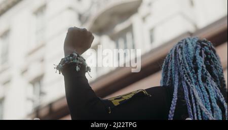 London, Großbritannien -03 19 2022: Eine schwarze Frau, die sich beim Protest die Faust hebt und auf die Menge auf der Regent Street zeigt, zum jährlichen ‘Marsch gegen Rassismus’. Stockfoto