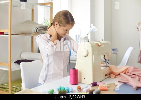 Schneiderin leidet unter Nackenschmerzen, die an der Nähmaschine arbeiten Stockfoto