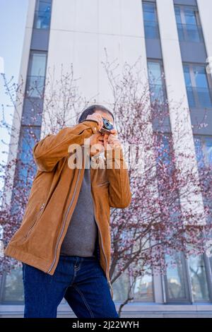 Der ältere Mann, der mit seiner alten Filmkamera in der Stadt fotografiert Stockfoto