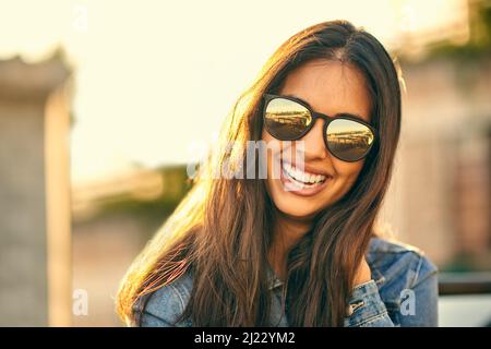 Sonne ist draußen, Sonnenbrille an, bereit für Viel Spaß. Porträt einer attraktiven jungen Frau, die den Tag draußen auf einem Dach verbringt. Stockfoto