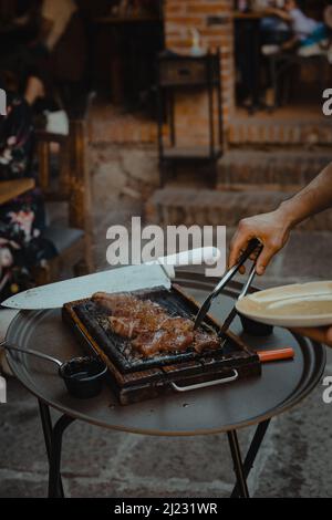 Grillküche. Der Koch schneidet geräucherte Schweinerippen mit einem Messer. Stockfoto