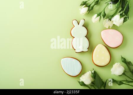 Frohe Ostern. Postkarte mit Ostergebäck oder Lebkuchen und schönen Blumen auf hellgrünem Hintergrund. Draufsicht mit Platz für Ihre Grüße. Stockfoto