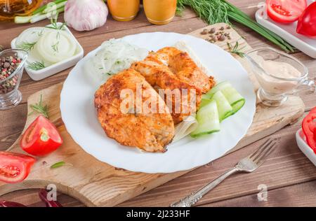 Gegrillte Hähnchenfleischspieße mit frischem Gemüse auf einem weißen Teller auf einem dunklen Holzhintergrund. Stockfoto