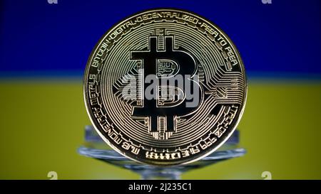 Golden Kryptowährung Bitcoin vor der Flagge der Ukraine. Der Fokus liegt auf der Münze vorne. Stockfoto