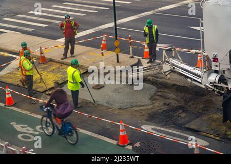 Arbeiter gießen Zement über eine Ausgrabung auf der Straße, nachdem sie am Samstag, dem 19. März 2022, die Untertagearbeiten an der Ninth Avenue in Chelsea in New York abgeschlossen haben. (© Richard B. Levine) Stockfoto