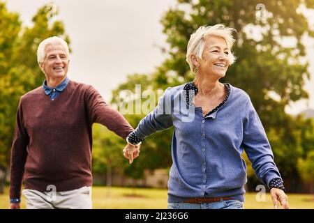 Liebe hält eine Ehe am Leben. Aufnahme eines glücklichen älteren Paares, das einen Spaziergang im Park macht. Stockfoto