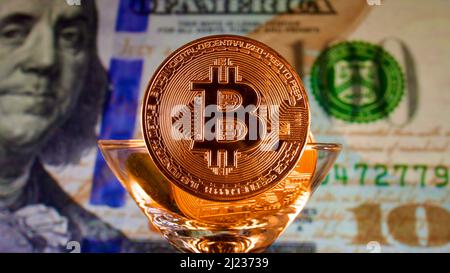 Papiergeld USD Dollar, Goldkrypto-Währung Bitcoin vor amerikanischen Dollar. Der Fokus liegt auf der Papierbanknote auf der Rückseite. Stockfoto