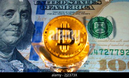 Papiergeld USD Dollar, Goldkrypto-Währung Bitcoin vor amerikanischen Dollar. Der Fokus liegt auf der Papierbanknote auf der Rückseite. Stockfoto