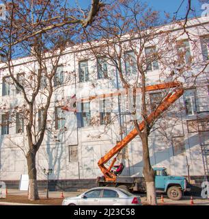 Dnepropetrovsk, Ukraine - 02.09.2022: Baumeister in einem Krankorb repariert die Beschichtung einer Metallstruktur an der Wand der Fassade eines Gebäudes. Stockfoto