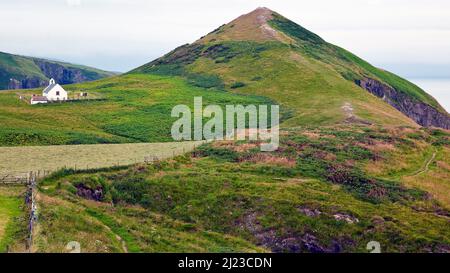 Blick auf Foel-y-Mwnt und die Holy Cross Church vom Cardigan Coastal Path in Ceredigion Wales Stockfoto