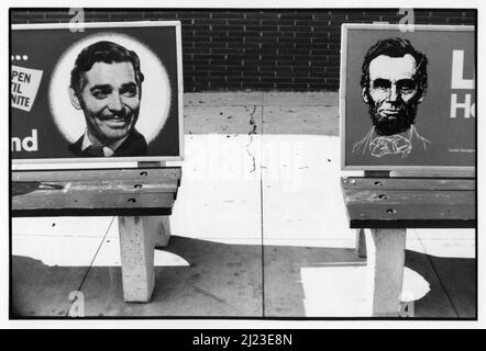 Bushaltestellen-Bänke in Los Angels mit Bildern von Clark Gable und Abraham Lincoln, die in dieser schwarz-weißen Stadtlandschaft um 1970s ein seltsames Paar machten. Stockfoto