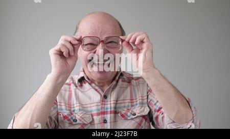 Gutaussehender älterer Mann, der lächelnd durch die Brille schaut. Studioaufnahme Stockfoto