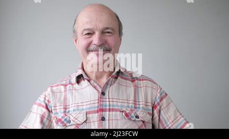 Lächelnder, reifer, lockerer hispanischer Mann mit Brille und Blick auf die Kamera. Studio-Video Stockfoto