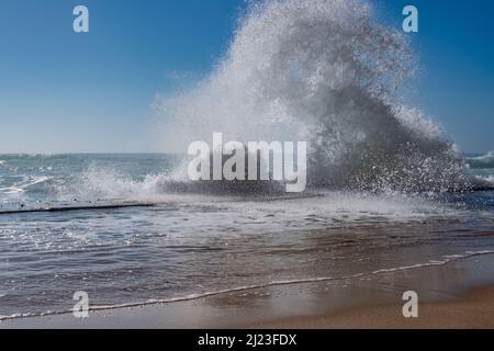 Schaumige Wellen, die hoch gegen den blauen Himmel plätschern Stockfoto