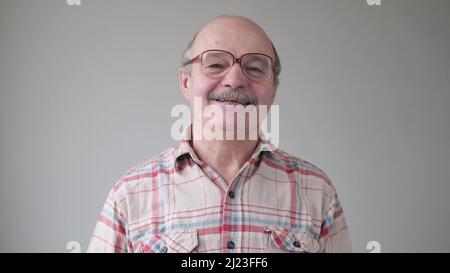 Lächelnder, reifer, lockerer hispanischer Mann mit Brille und Blick auf die Kamera. Studio-Video Stockfoto