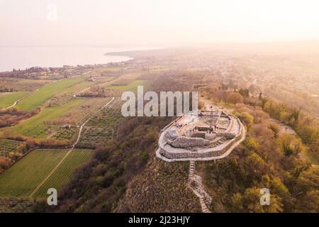 Luftaufnahme der Festung mit einem Kreuz auf einem Hügel im Hintergrund Gardasee. Panorama auf die rocca di manerba von oben. Stockfoto