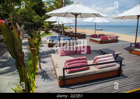 Sonnenliegen, Tische, Stühle am Strand im Griya Santrian Hotel in Sanur, Bali, Indonesien. Stockfoto