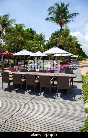 Sonnenliegen, Tische, Stühle am Strand im Griya Santrian Hotel in Sanur, Bali, Indonesien. Stockfoto