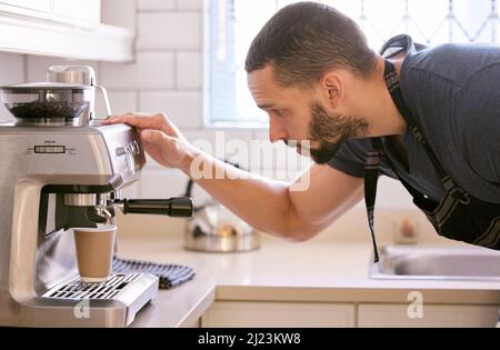 Ich habe mich schon auf diese Tasse Kaffee gefreut. Aufnahme eines jungen Mannes, der eine Tasse Kaffee zubereitet. Stockfoto