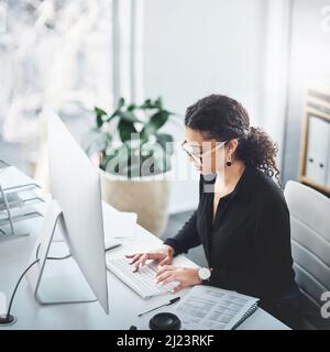 Nichts wird einen fokussierten Geist zerbrechen wie sie. Aufnahme einer jungen Geschäftsfrau, die in einem Büro an einem Computer arbeitet. Stockfoto