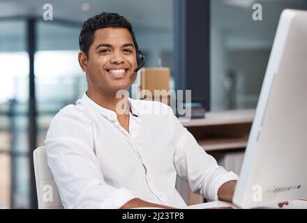 Kundenorientiert, um die Kundenzufriedenheit zu gewährleisten. Porträt eines jungen Geschäftsmannes, der an einem Computer in einem Callcenter arbeitet. Stockfoto