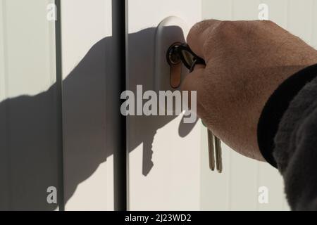 Detail eines Mannes, der eine Bürotür mit farbigen Schlüsseln öffnet Konzept der Türen zu öffnen Stockfoto