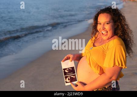 Schwanger Frau mit ihrem Baby, Sonographie. Glückliche, werdende Dame genießt das erste Foto ihres ungeborenen Kindes und erwartet ihr zukünftiges Leben Stockfoto