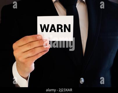 Das Wort STOP auf einer weißen Karte in den Händen eines Geschäftsmannes geschrieben Stockfoto