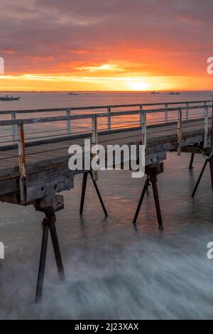 Ein glühender Sonnenaufgang über dem legendären Beachport Jetty mit langer Belichtung im Südosten von Südaustralien, aufgenommen am 20. 2022. Februar Stockfoto