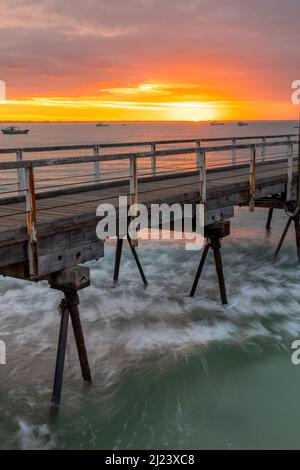 Ein glühender Sonnenaufgang über dem legendären Beachport Jetty mit langer Belichtung im Südosten von Südaustralien, aufgenommen am 20. 2022. Februar Stockfoto