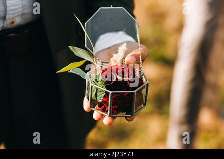 Hochzeitszeremonie im Boho-Stil. Glasbox mit Eheringen Stockfoto