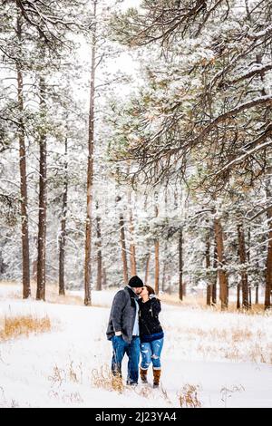 Mann und Frau küssen in einem verschneiten Kiefernwald Stockfoto