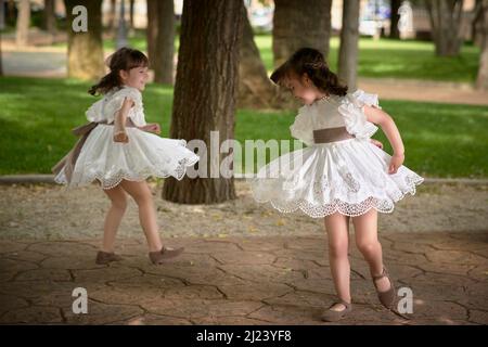 Kommunion Mädchen Zwillinge tanzen in einem Park Stockfoto